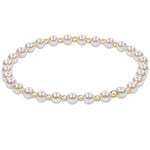 An enewton gold-colored bracelet featuring a series of round pearl beads and smaller gold-filled beads, hand-beaded on elastic. Available at Be Charmed