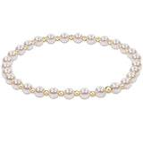 An enewton gold-colored bracelet featuring a series of round pearl beads and smaller gold-filled beads, hand-beaded on elastic. Available at Be Charmed