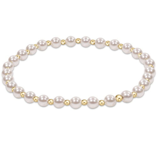 An enewton gold-colored bracelet featuring a series of round pearl beads and smaller gold-filled beads, hand-beaded on elastic. Available at Be Charmed