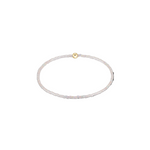 Thin white beaded bracelet with a gold clasp on a white background. Available at Be Charmed