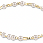 An enewton bracelet featuring a series of pearl beads with gold accents on a gold-colored band. Available at Be Charmed
