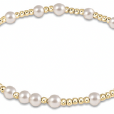 An enewton bracelet featuring a series of pearl beads with gold accents on a gold-colored band. Available at Be Charmed