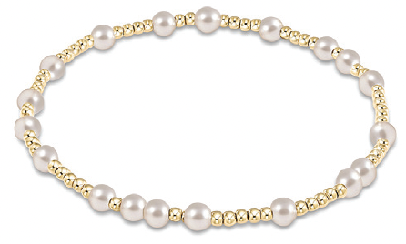 An enewton bracelet featuring a series of pearl beads with gold accents on a gold-colored band. Available at Be Charmed