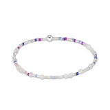A beaded bracelet featuring white faux pearls, silver-toned beads, and small accent beads in purple, blue, and pink, arranged in a circular shape on a white background. Available at Be Charmed