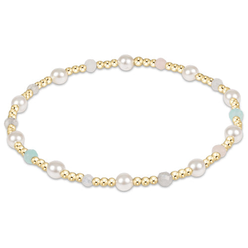 A gold-colored bead bracelet with white pearls and multicolored gemstones. Available at Be Charmed