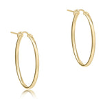 A pair of oval gold 1 inch hoop earrings with a smooth finish. Available at Be Charmed