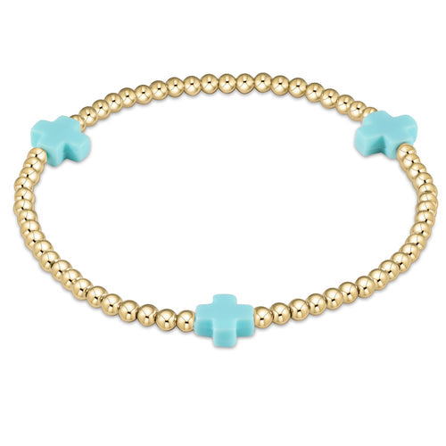 An enewton gold-filled bracelet with turquoise beads and a signature cross design, featuring a chain-like pattern. Available at Be Charmed