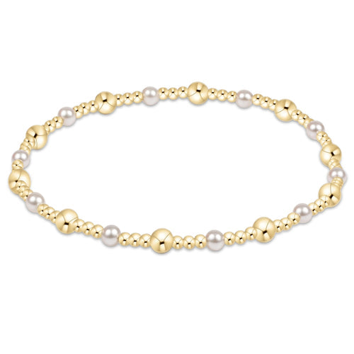 An enewton gold-colored bracelet with a pattern of gold-filled beads and white pearls, designed for stacking. Available at Be Charmed