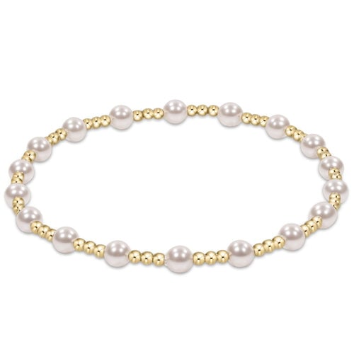 An enewton bracelet with white pearls and gold beads, arranged in a pattern with gold beads on the ends and a flexible band. Available at Be Charmed