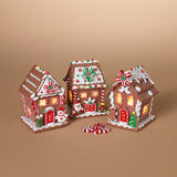 Three decorated gingerbread houses on a beige background. Available at Be Charmed