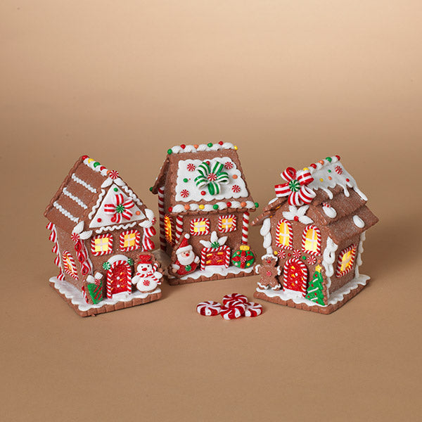 Three decorated gingerbread houses on a beige background. Available at Be Charmed