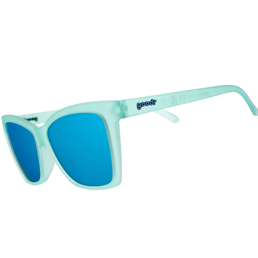 Sunglasses with blue lenses and light green frame on a white background. Available at Be Charmed