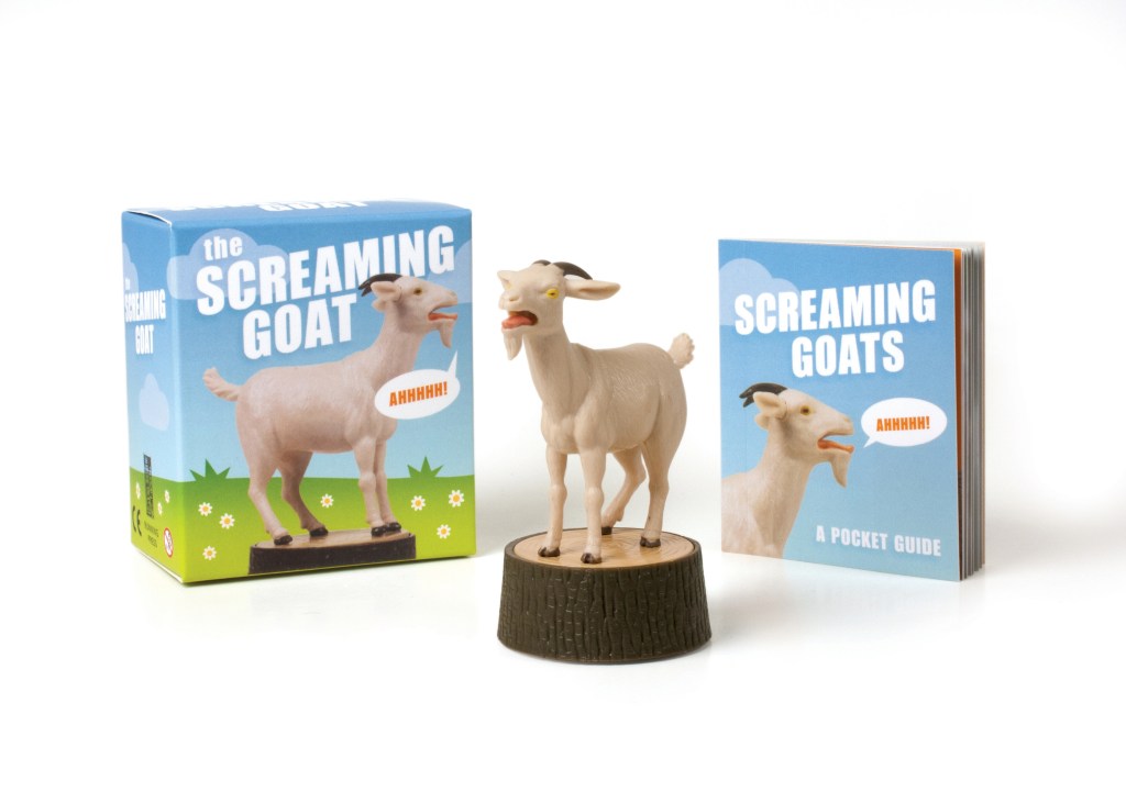 A toy set titled 'The Screaming Goat' shown with its blue illustrated box, a small goat figurine on a log base, and a matching pocket guide book on a white background. Available at Be Charmed