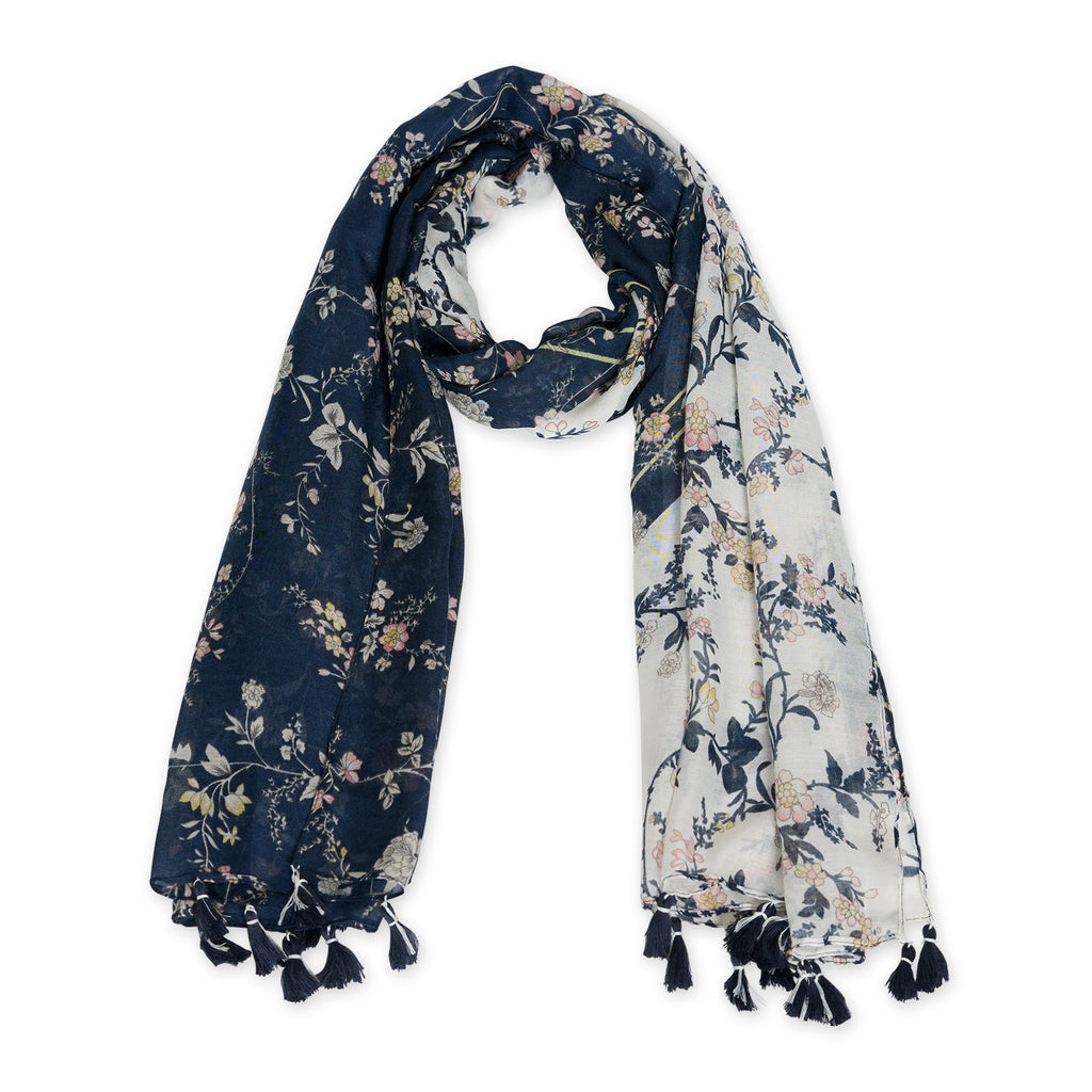 A navy floral scarf with tassels spread out on a plain surface. Available at Be Charmed