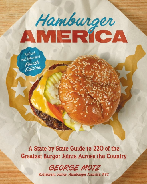 Book cover of 'Hamburger America' with a burger illustration on a wooden surface. Available at Be Charmed