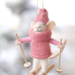 Decorative mouse ornament in pink winter clothing with skis on a blurred snowy background. Available at be Charmed
