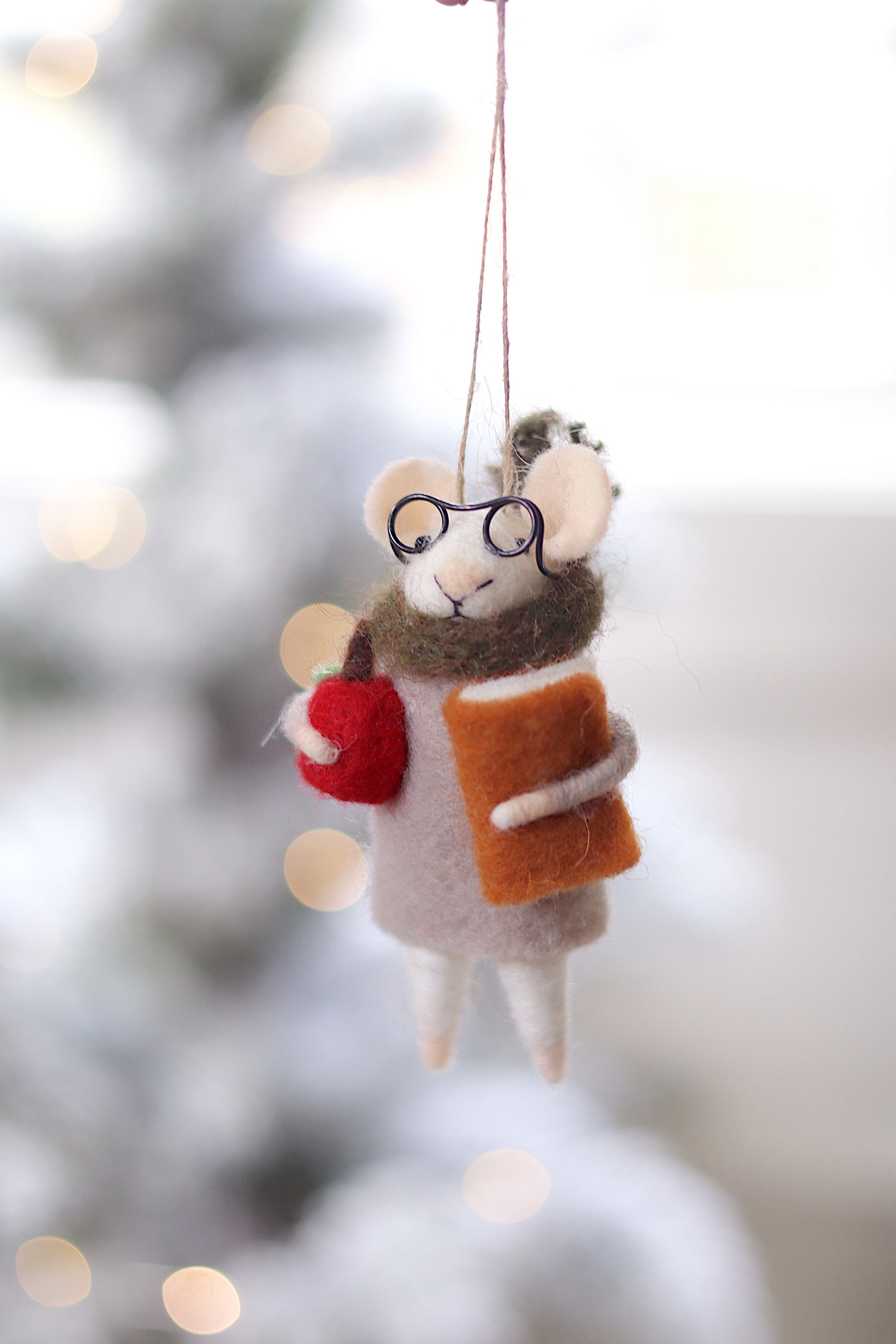 Decorative mouse ornament with glasses and a book, hanging against a blurred festive background. Available at Be Charmed