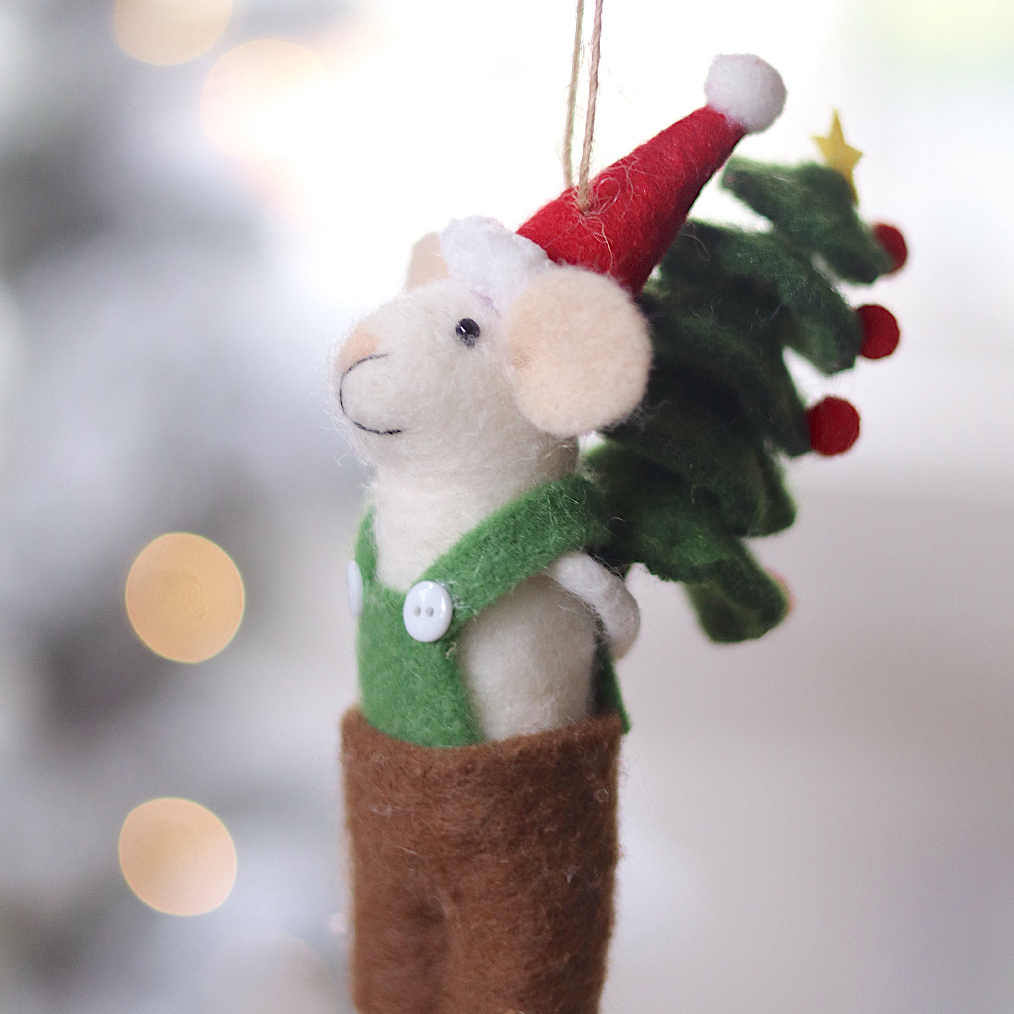 Decorative mouse ornament with a Santa hat and Christmas tree, hanging against a blurred festive background. Available at Be Charmed