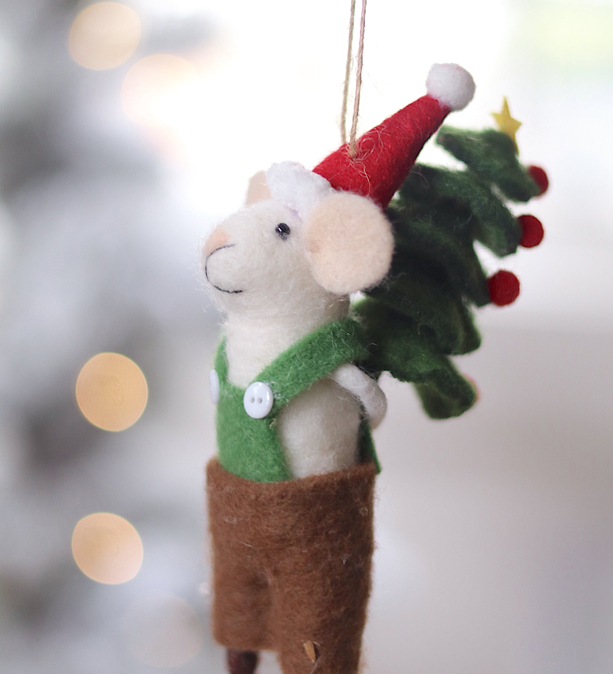 Decorative mouse ornament with a Santa hat and Christmas tree, hanging against a blurred festive background. Available at Be Charmed