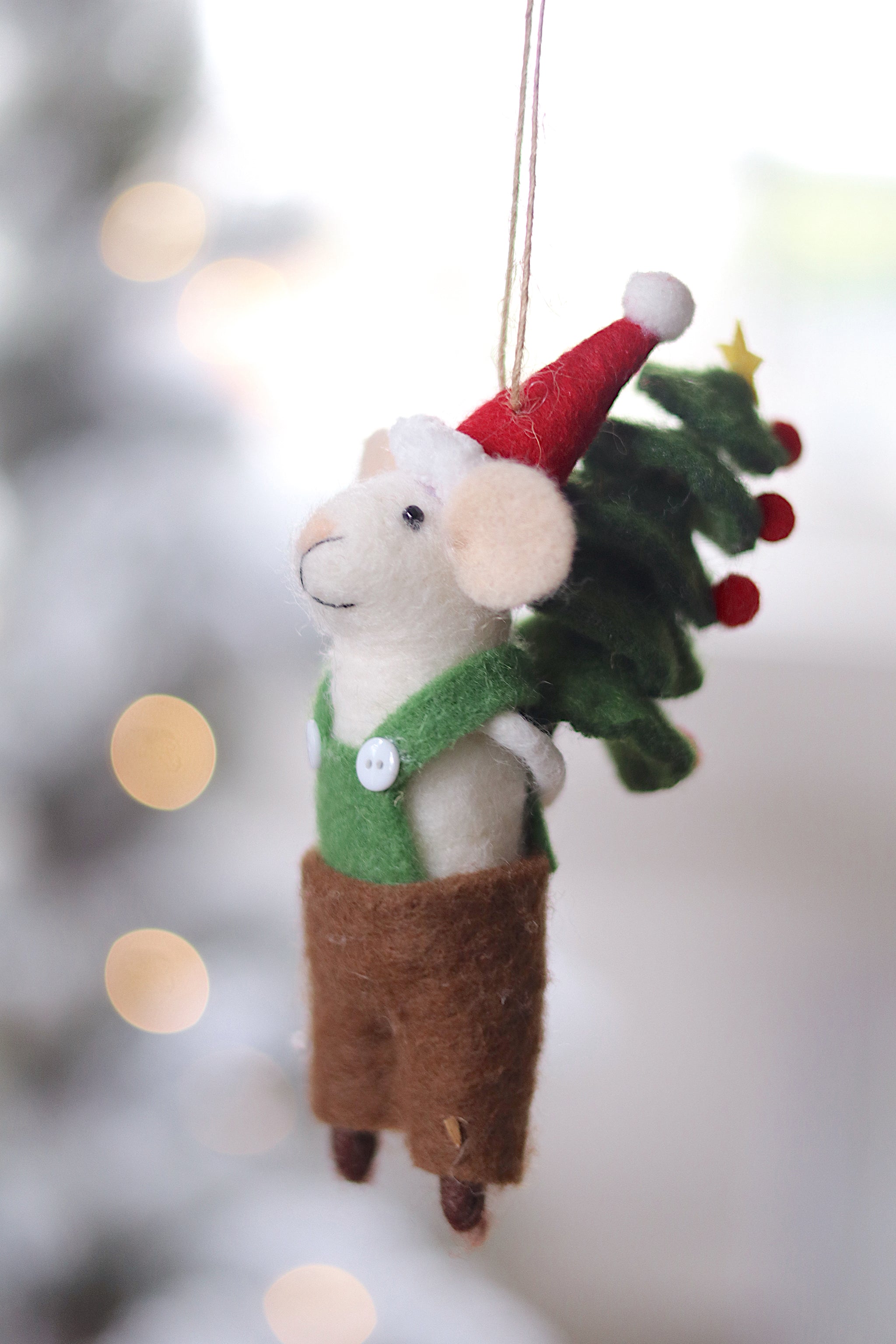 Decorative mouse ornament with a Santa hat and Christmas tree, hanging against a blurred festive background. Available at Be Charmed
