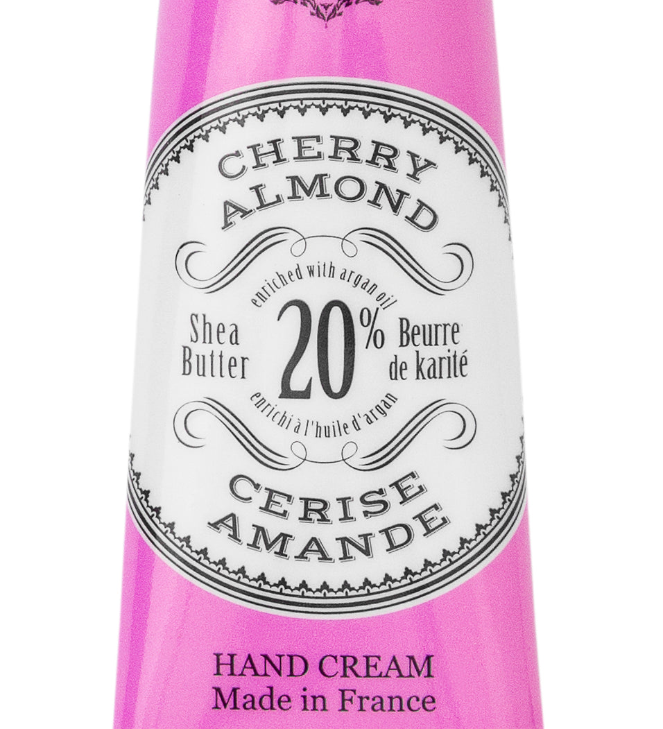 Purple hand cream tube labeled 'Cherry Almond' with branding on a white background. Available at Be Charmed