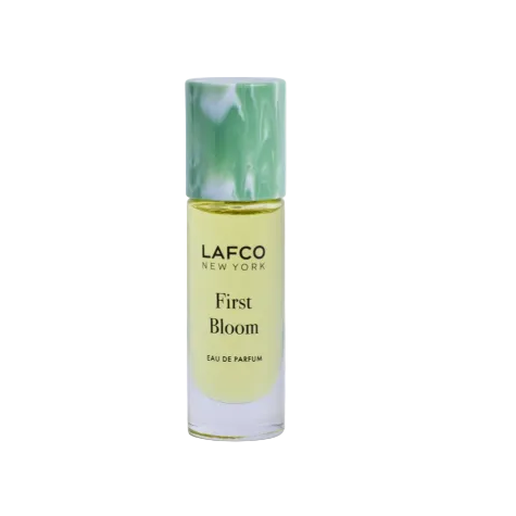 A bottle of LAFCO New York First Bloom Eau de Parfum, featuring a light green marble-patterned cap and pale yellow-green liquid inside a clear glass bottle, set against a plain white background. Available at Be Charmed