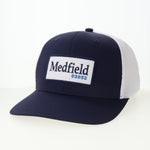 Navy and white cap with 'Medfield 02052' logo on a white background. Available at Be Charmed