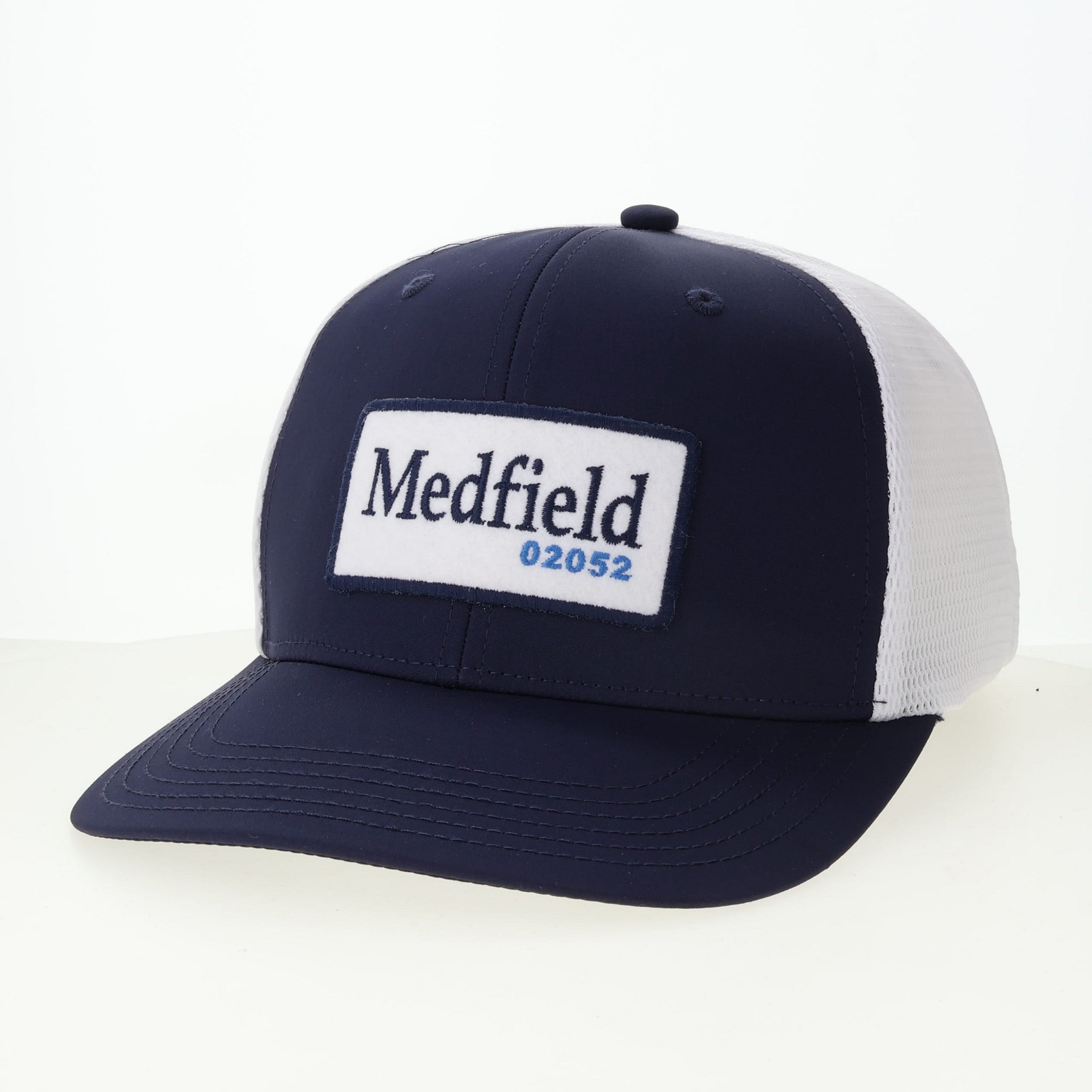 Navy and white cap with 'Medfield 02052' logo on a white background. Available at Be Charmed