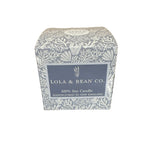 Lola & Bean Co. candle packaging on a dark surface with white background. Available at Be Charmed. 