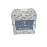 Lola & Bean Co. candle packaging on a dark surface with white background. Available at Be Charmed. 