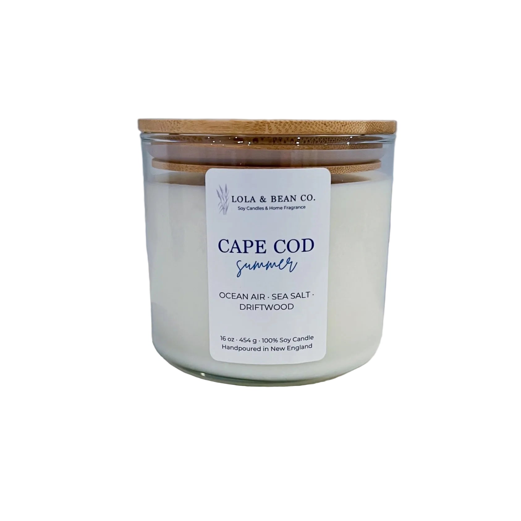 Candle labeled 'Cape Cod Summer' by Lola & Bean Co. on a wooden block with a white background. Candle is handmade in Massachusetts. Available at Be Charmed