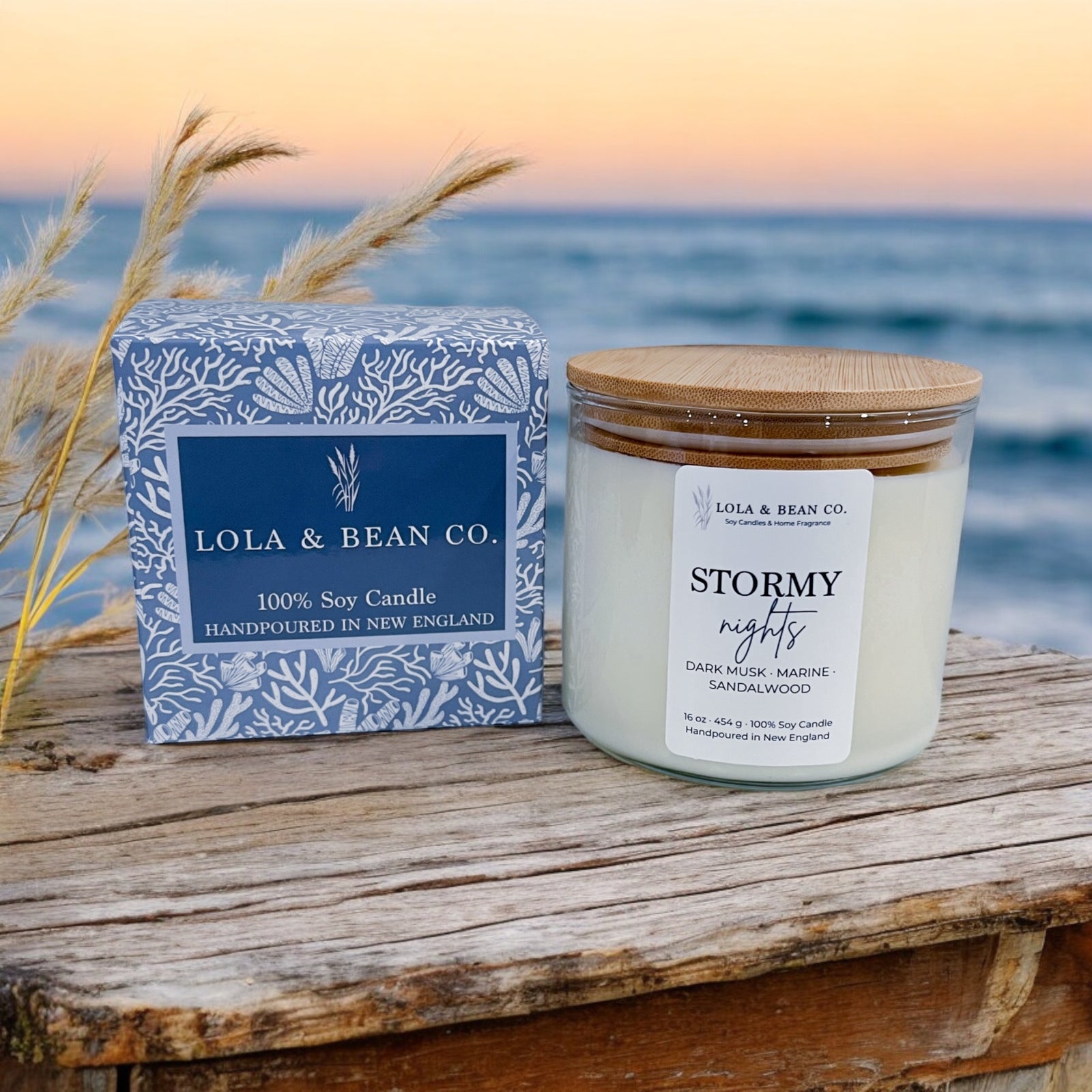 Lola & Bean Co. candle and packaging on a wooden surface with a scenic background. Available at Be Charmed