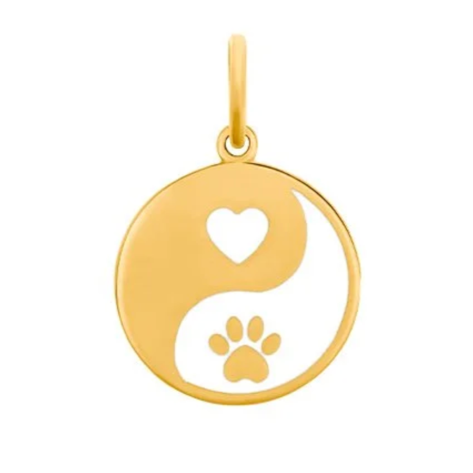 Gold pendant with yin yang design featuring a heart and paw print on a white background. Available at Be Charmed. 