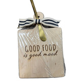Wooden board with 'Good food is good mood' text, wrapped in cellophane with a ribbon and gold bow. Available at Be Charmed