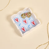 Gold earrings on a decorative tray with lobster design on a beige background. Available at Be Charmed