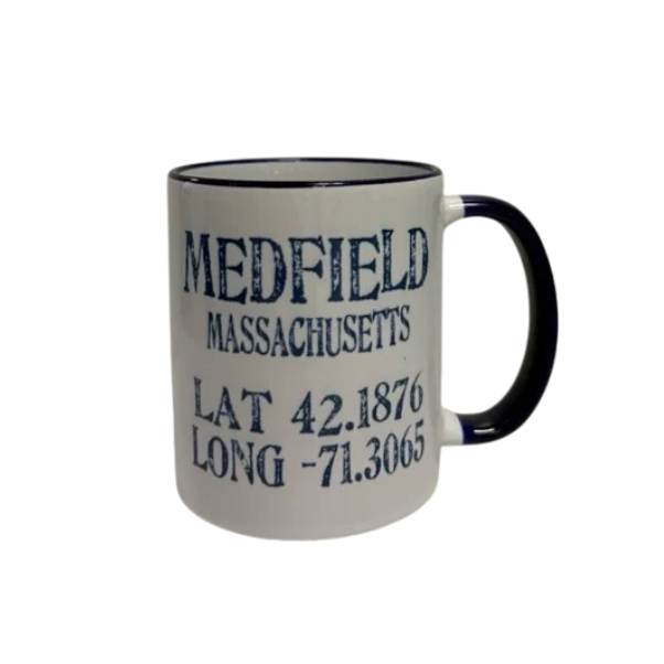 A white ceramic mug with a navy handle and rim, printed with the text 'MEDFIELD MASSACHUSETTS' and coordinates 'LAT 42.1876' and 'LONG -71. Available at Be Charmed
