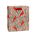 A Rifle Paper Co gift bag with a repeating pattern of red cardinals, green leaves, and small red flowers on a cream background, featuring red paper handles.  Available at Be Charmed