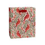 A Rifle Paper Co gift bag with a repeating pattern of red cardinals, green leaves, and small red flowers on a cream background, featuring red paper handles.  Available at Be Charmed
