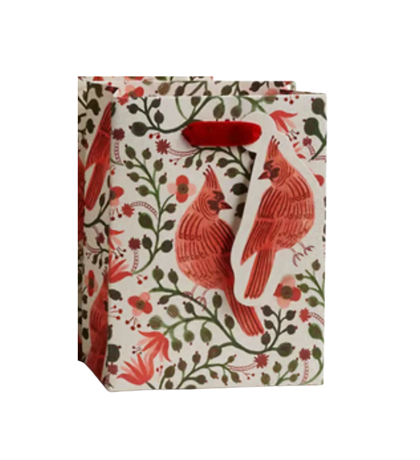 A Rifle Paprer Co gift bag with a cream background, featuring a red cardinal and green floral pattern, with red paper handles. Available at Be Charmed