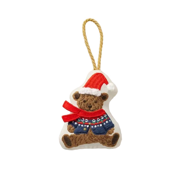 A small Rifle Paper Co embroidered Christmas ornament shaped like a teddy bear wearing a red Santa hat and a red patterned sweater, hanging from a tan string on a white background. Available at Be Charmed