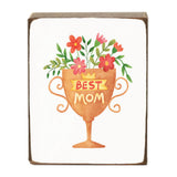 Decorative block with a cup of flowers and 'Best Mom' text on a white background. Available at Be Charmed