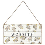 Decorative 'welcome' sign with oyster shell pattern on a white background. Available at Be Charmed