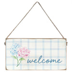 Decorative sign with flowers and 'welcome' text on a plaid background. Available at Be Charmed
