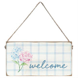 Decorative sign with flowers and 'welcome' text on a plaid background. Available at Be Charmed