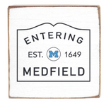 Rustic Marlin magnet with 'Entering Medfield' text and a blue 'M' on a white background. Available at Be Charmed