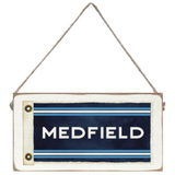 Rectangular twine sign with 'MEDFIELD' text on a blue background, hanging by a string. Available at Be Charmed