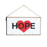 A rustic wooden hanging sign with the word 'HOPE' written in black letters and a red heart shape filling the letter 'O'. Available at Be CHarmed