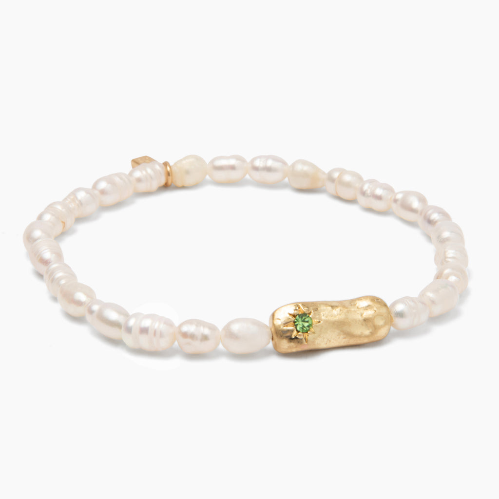 A bracelet with white pearls and gold-colored medallions, featuring inset crystals on one medallion. Available at Be Charmed