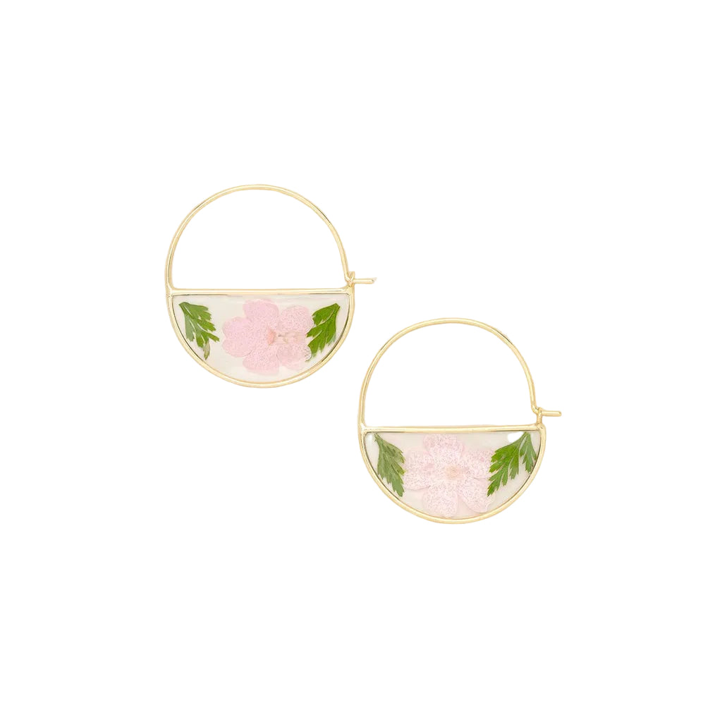 Gold hoop earrings with pink floral elements on a beige background