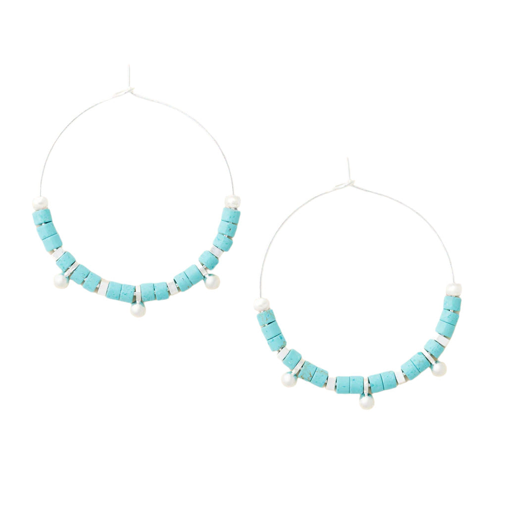 A pair of hoop earrings with blue stone discs and silver accents, arranged in a hoop shape. Available at Be Charmed